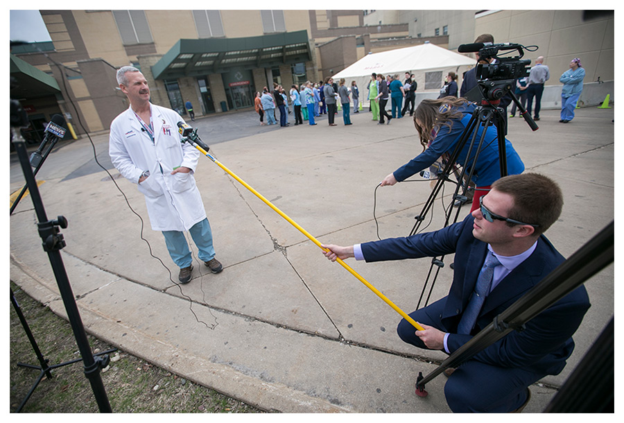 Reporters use boom poles with microphones to maintain at least six feet of distance from Dr. James Cole