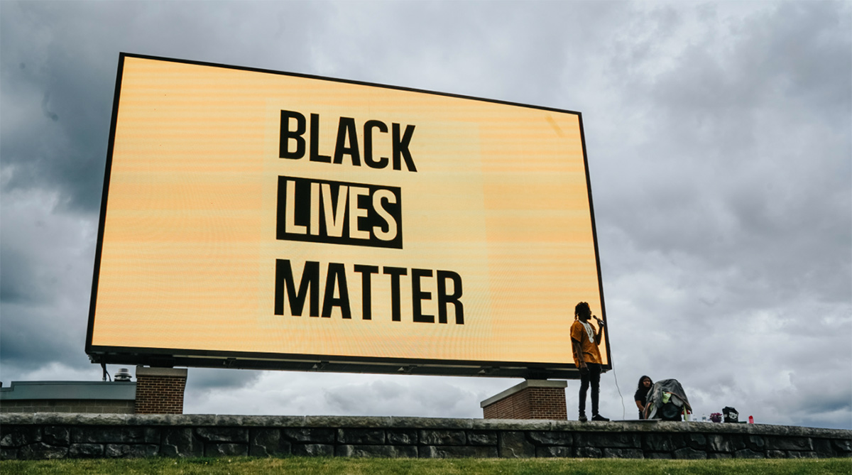 BLM sign with student in front at Wildcat Stadium