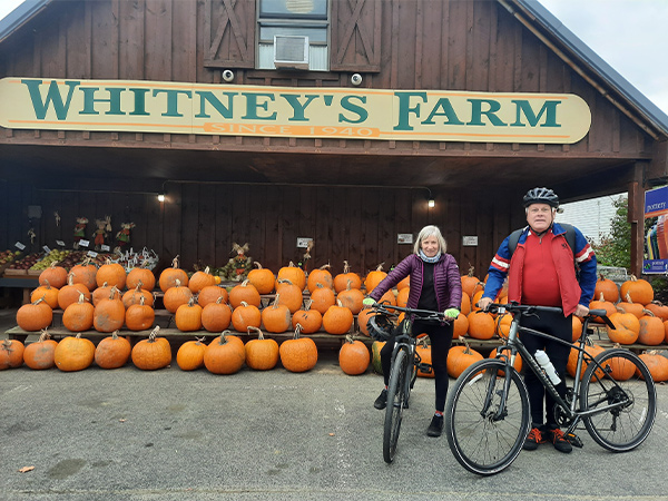 Jackie Lacroix and Richard Whitney biking by Whitney's Farm