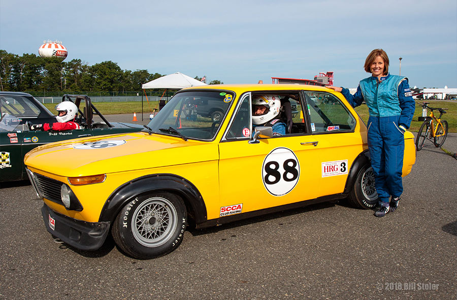 Margo Otey standing next to her bright yellow vintage BMW