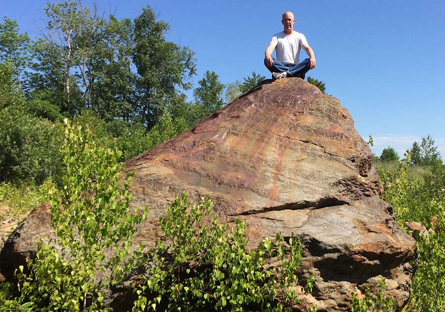 Stephen Cullen sitting on a rock in nature