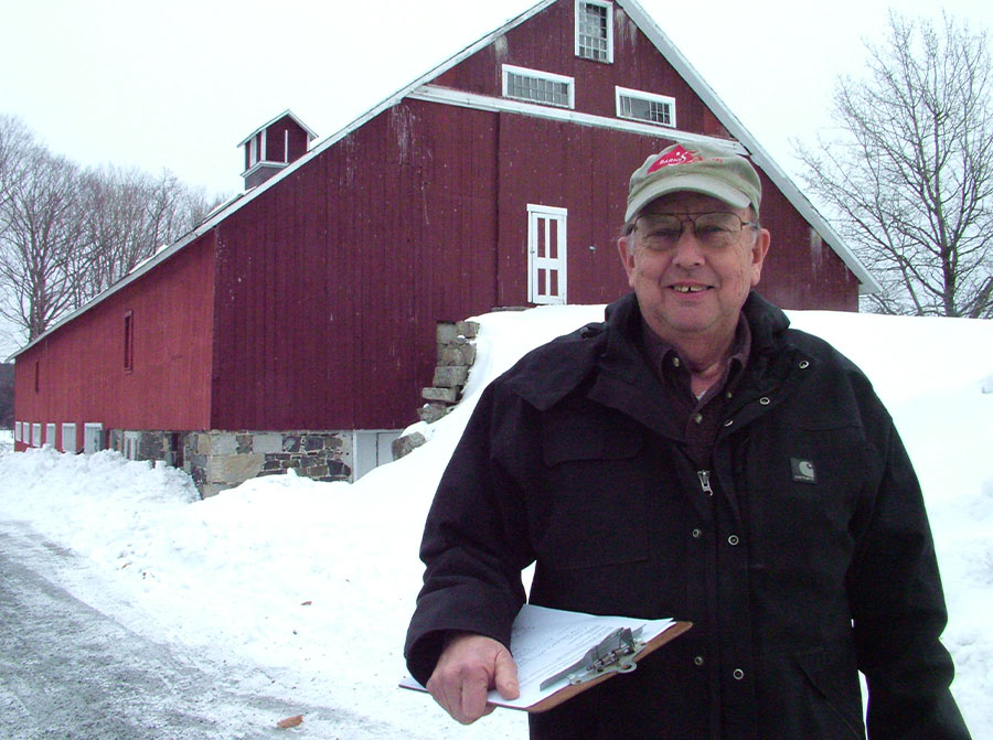 John Porter ’71 standing in front of an old red barn