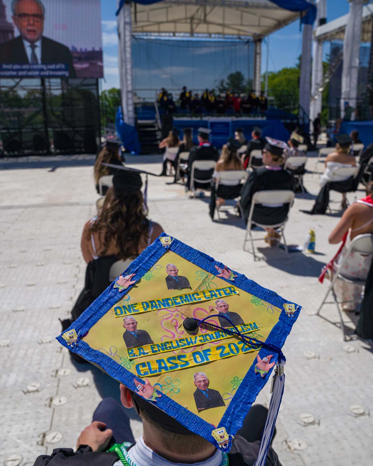 A student sports a Spongebob-themed graduation cap as he watches the commencement ceremony with his peers