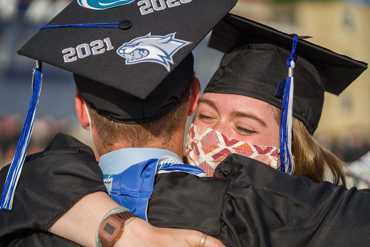 Two students celebrate and hug happily in their caps and gowns