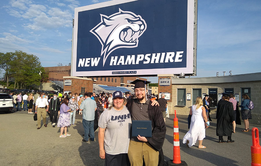 Michelle Conroy in front of a Wildcat New Hampshire sign with a graduating family member