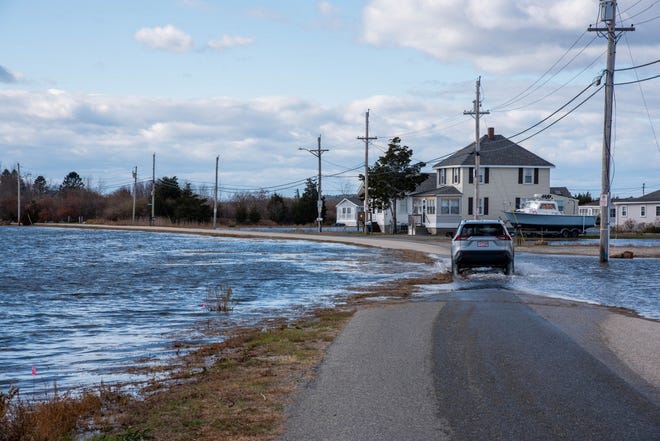 A driver attempts to pass on a frequently flooded road in Hampton, New Hampshire, amid flooding caused by a king tide.