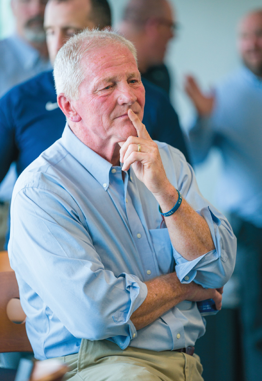 Coach Sean McDonnell ’78, listens to the emotional, reflective and funny speeches made by colleagues and former footballers at a going-away event in his honor earlier this summer