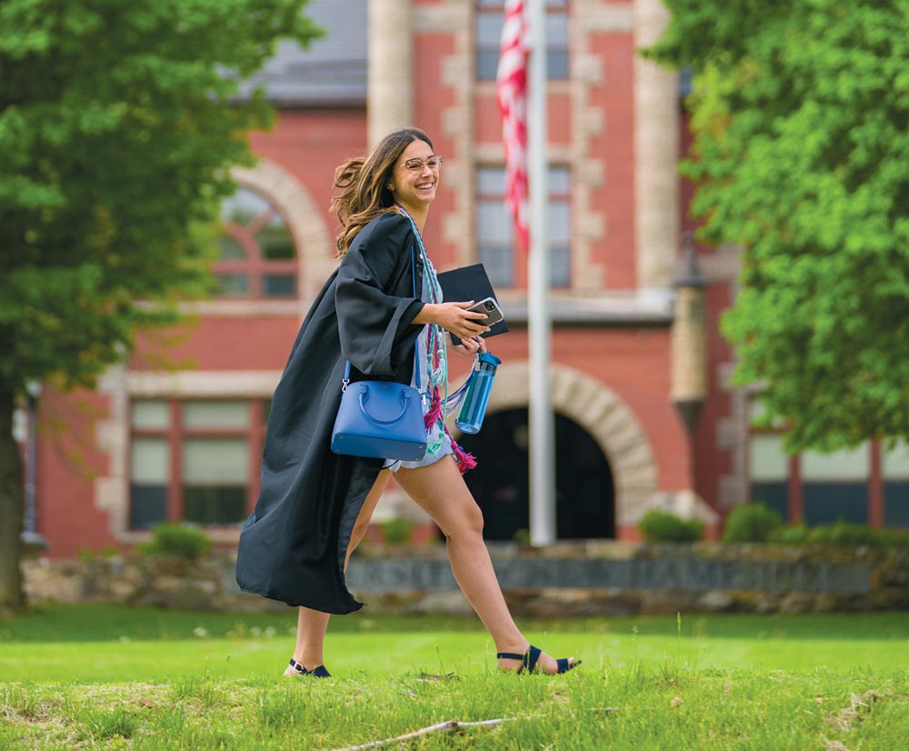 Female graduate walking across grass