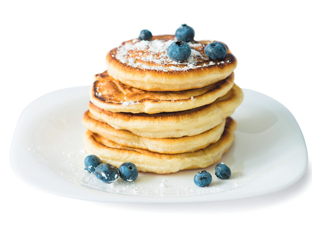 Stack of pancakes on plate with blueberries on top