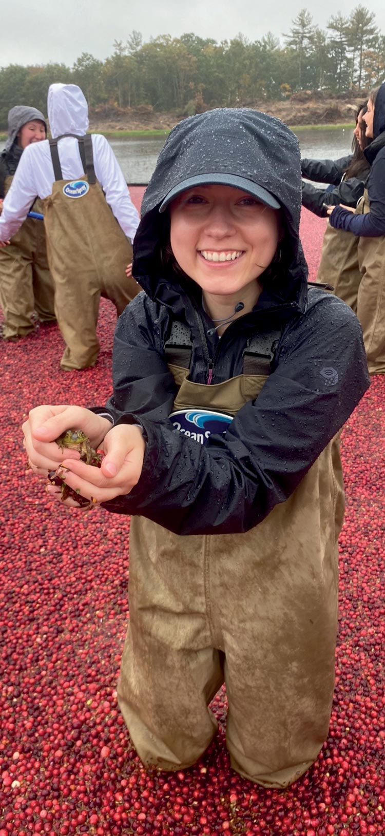 Jocelyn Therrien ’25 holding a frog in a cranberry bog