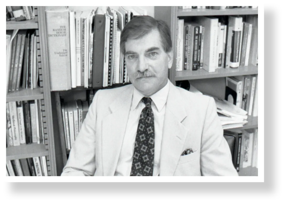 John Kayser with bookshelf behind him