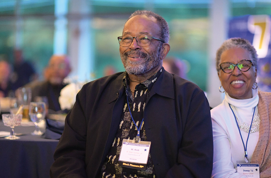 UNH alumni elderly individuals (a man and a woman) sitting next to each other smiling and laughing enjoying a good time