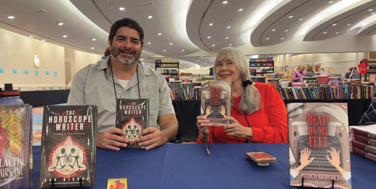 A man and woman sitting at a table for a book signing 