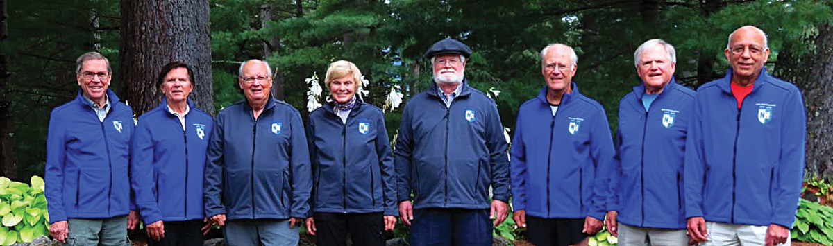 8 people in blue jackets side by side, smiling for a photo