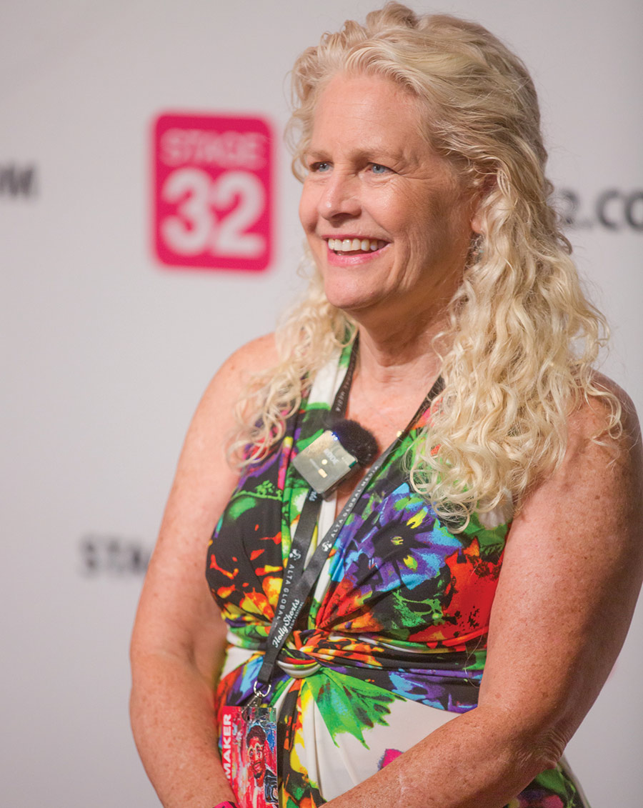 Close-up portrait photograph of Xochi Blymyer ’84 smiling in a multi-colored floral design pattern dress