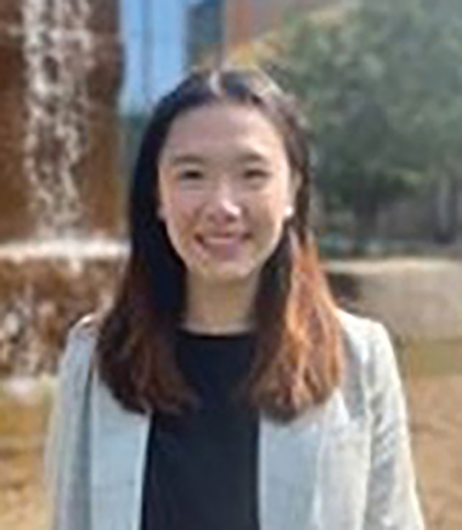 Close-up headshot portrait photograph of Vikki Jiang smiling in a light grey open blazer coat with a black blouse underneath as she is standing outside somewhere
