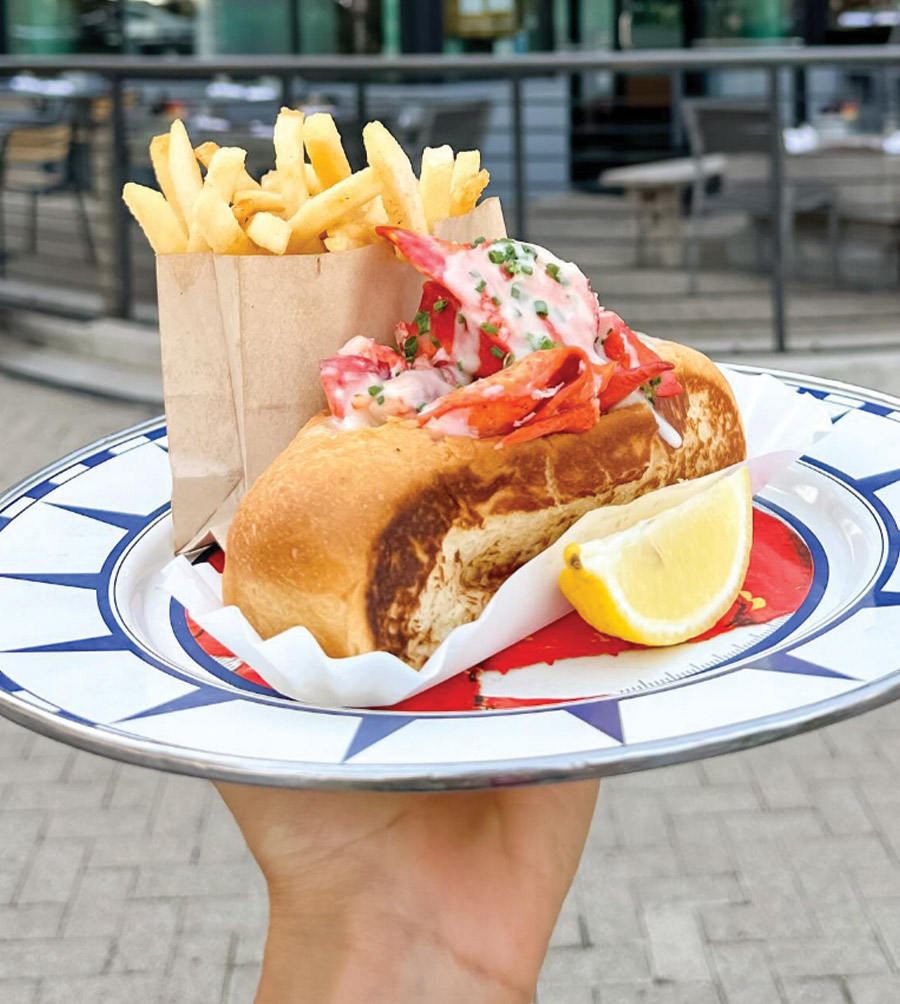 hand holding up a plate of lobster roll from The Walrus Oyster and Ale House