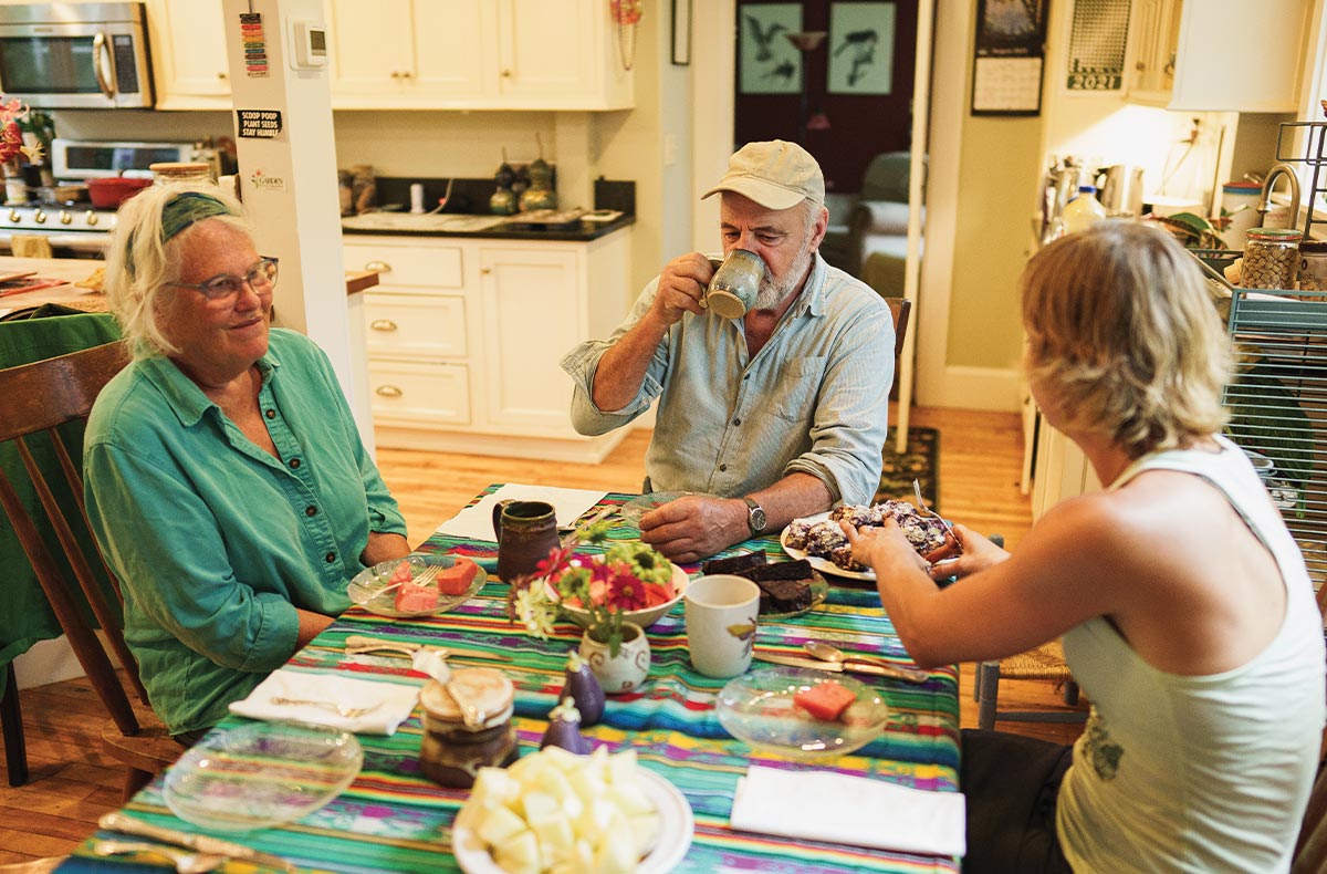 Bill and Eve Klotz sit at a dining room table with Joanne Ducas as they all share a meal