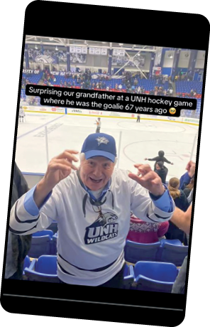Elderly man smiling and cheering in the stands at a UNH hockey game, wearing a UNH Wildcats jersey and cap. Text on the image reads, “Surprising our grandfather at a UNH hockey game where he was the goalie 67 years ago.”