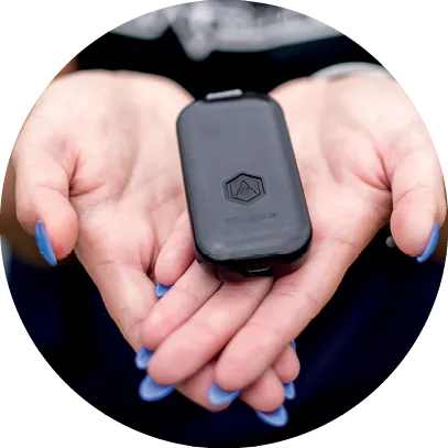 Hands holding a small black STATSports tracking device, with blue-painted fingernails visible.