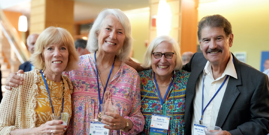 three woman and a man smiling for photo with arms around each other