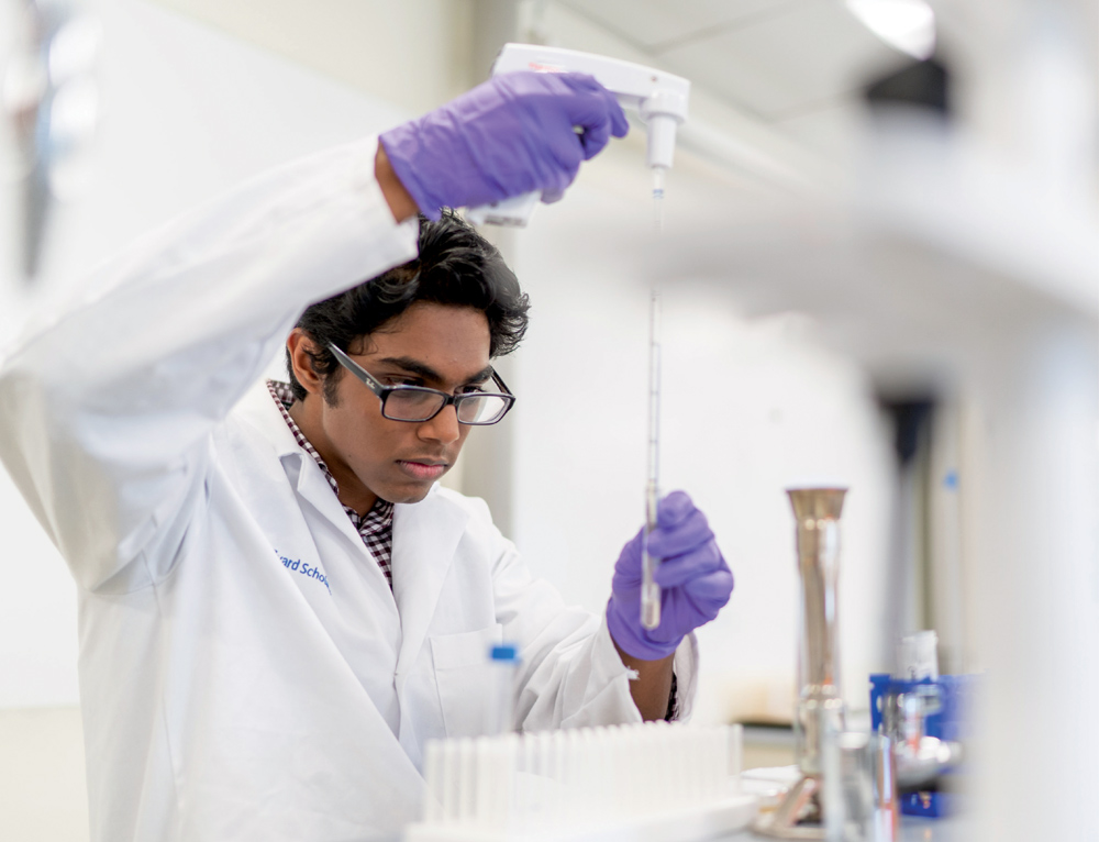 Person in a lab coat using a pipette in a lab.
