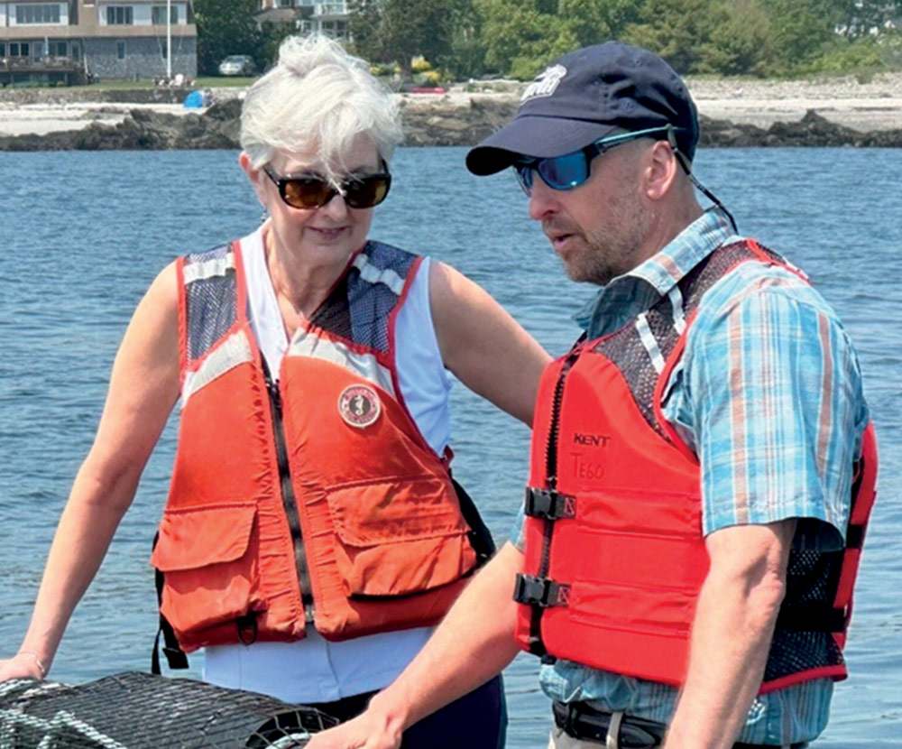 Two people in life vests near a body of water.