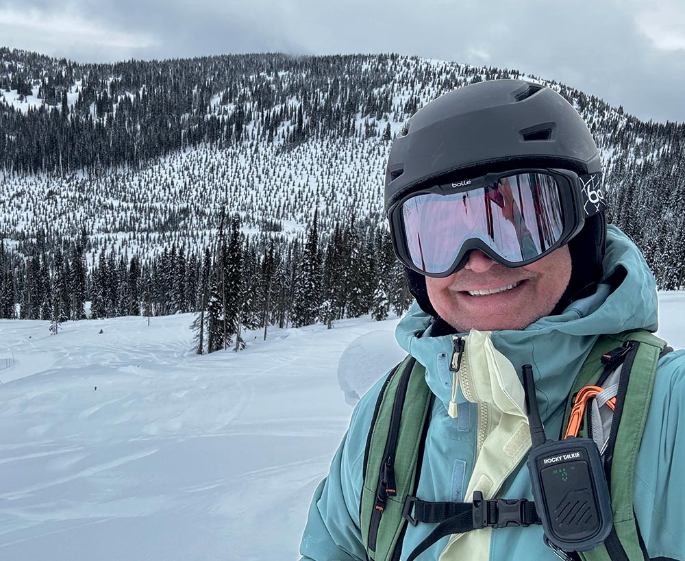 Person wearing ski snow gear taking a selfie in front of a snowy landscape 