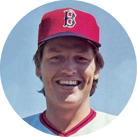 Portrait of a smiling baseball player wearing a red cap with a “B” logo and matching uniform.