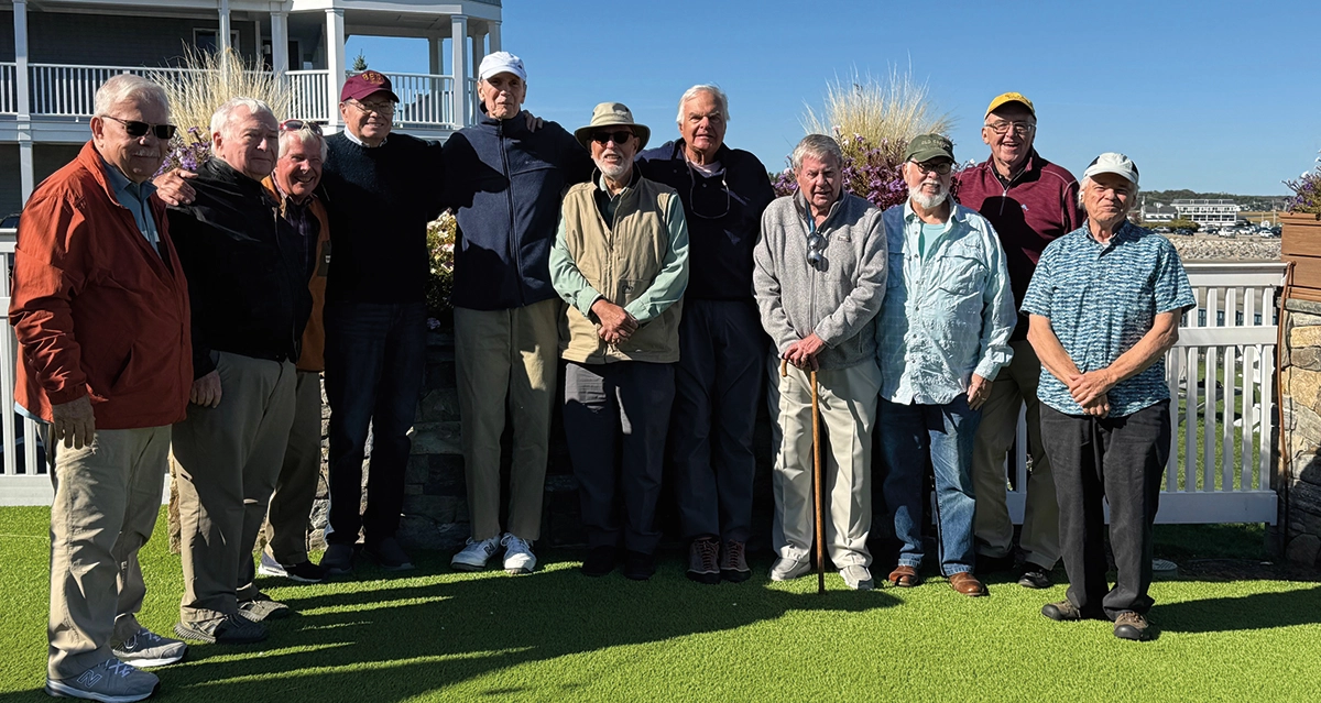 These late ’60s guys had a lunch gathering in Ogunquit, Maine, recently (pictured left to right): Peter Brown, Jim Chambers, Steve McGrath, Jim Crocker, Mike Franks, Rick Keller, Steve Rowe, Bill Keener, Ike Shepard, Mike Corbett, and Mike Donovan; Here the older men are standing together on a green turf area in front of a shingled house with a tower