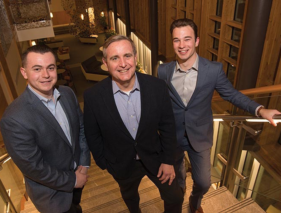John Turner standing on staircase with two interns
