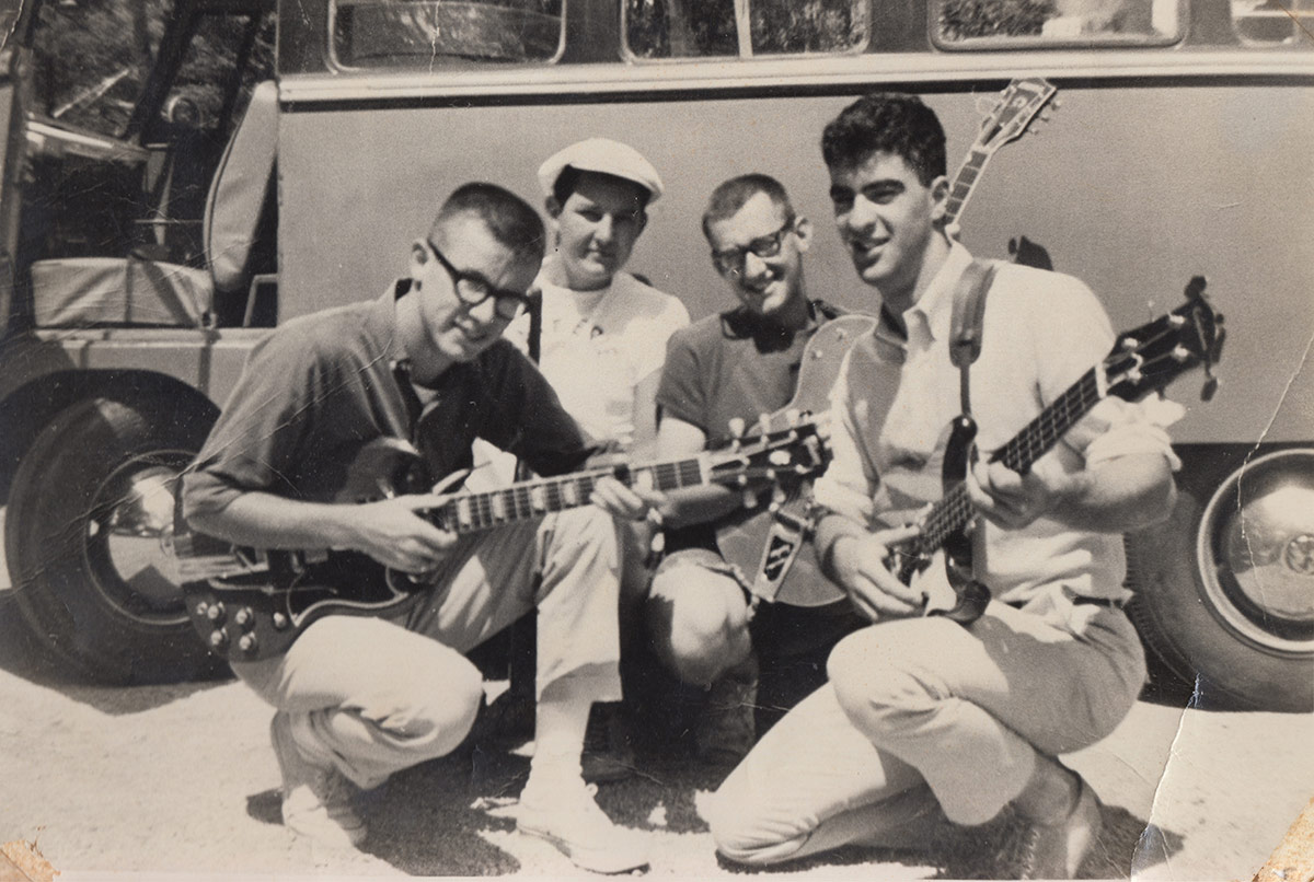 Black-and-white photo of James Woods '65 posing with his bandmates holding guitars.