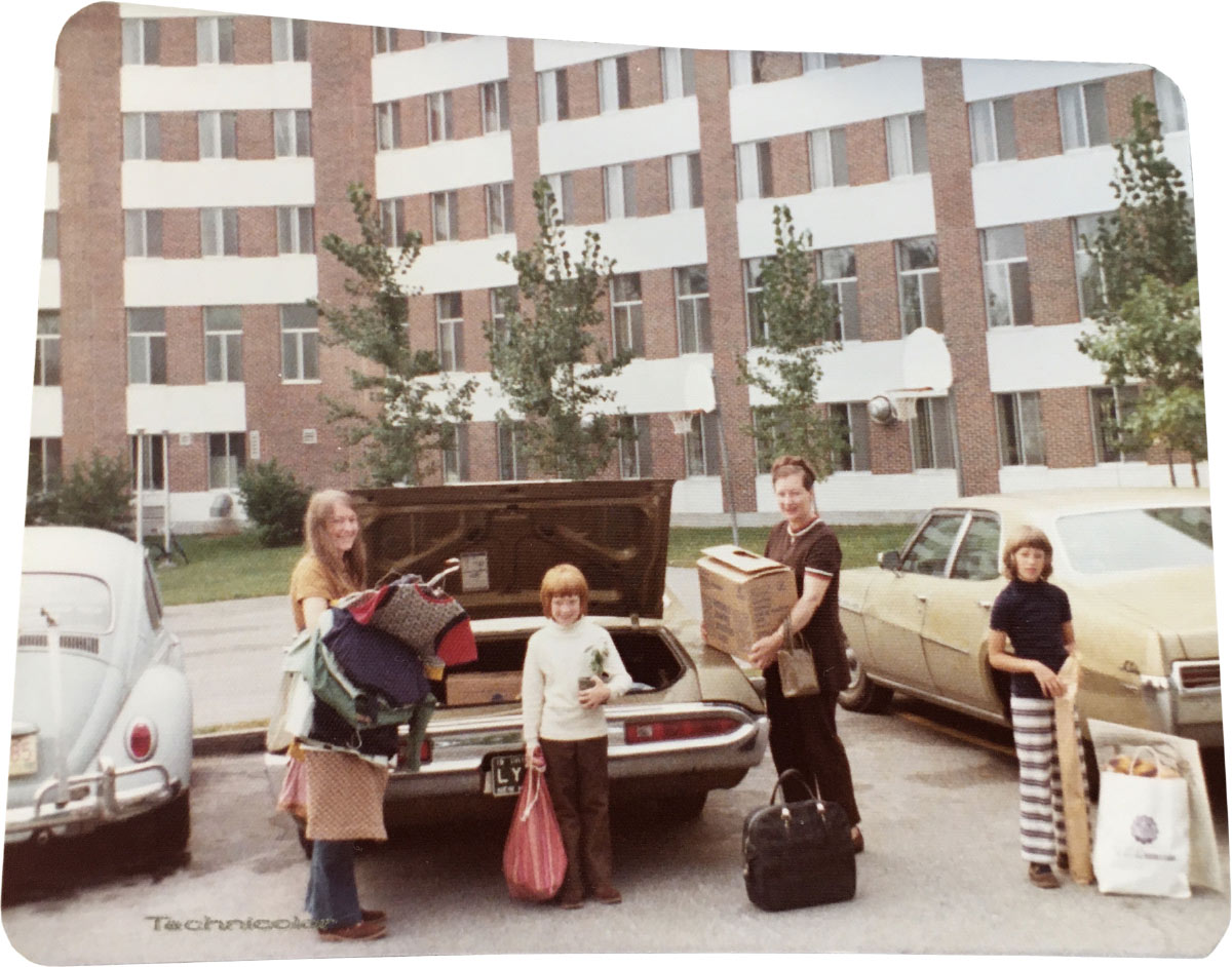 Vintage photo of family packing a car trunk outside Stoke Hall dormitory building.