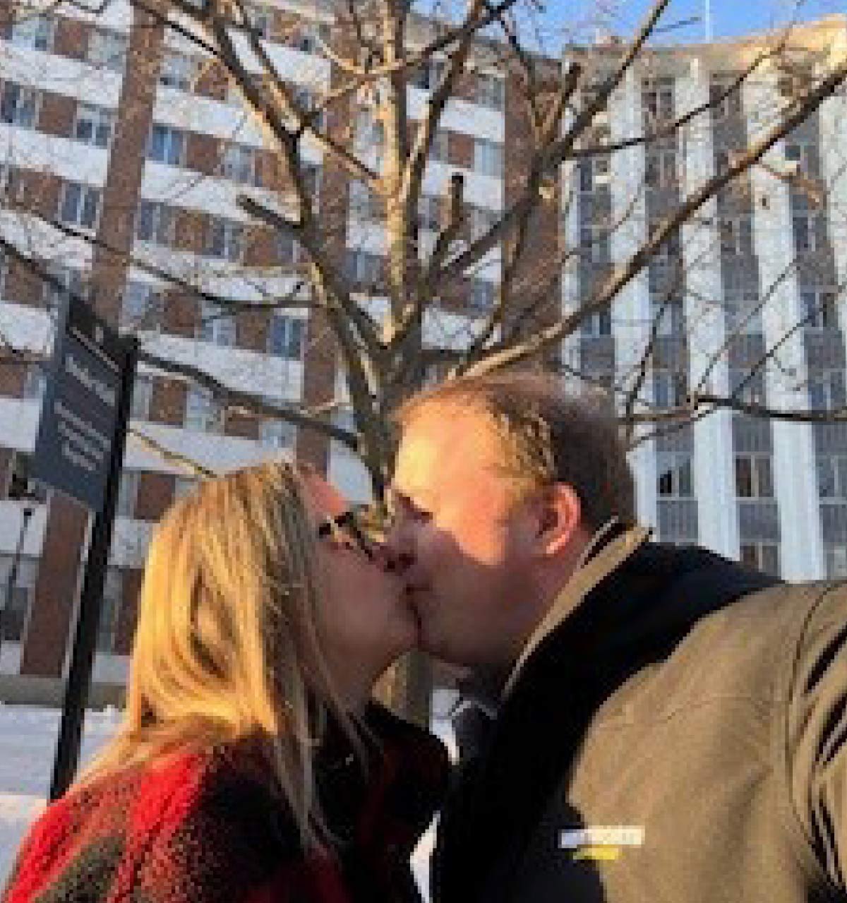 Couple kissing outdoors with the Stoke Hall campus building in the background.