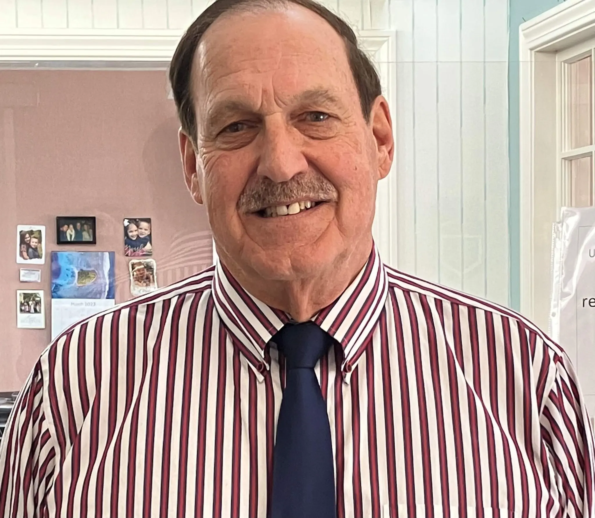 Rick Archambault ’74 smiles for a portrait while wearing a striped shirt and dark tie.