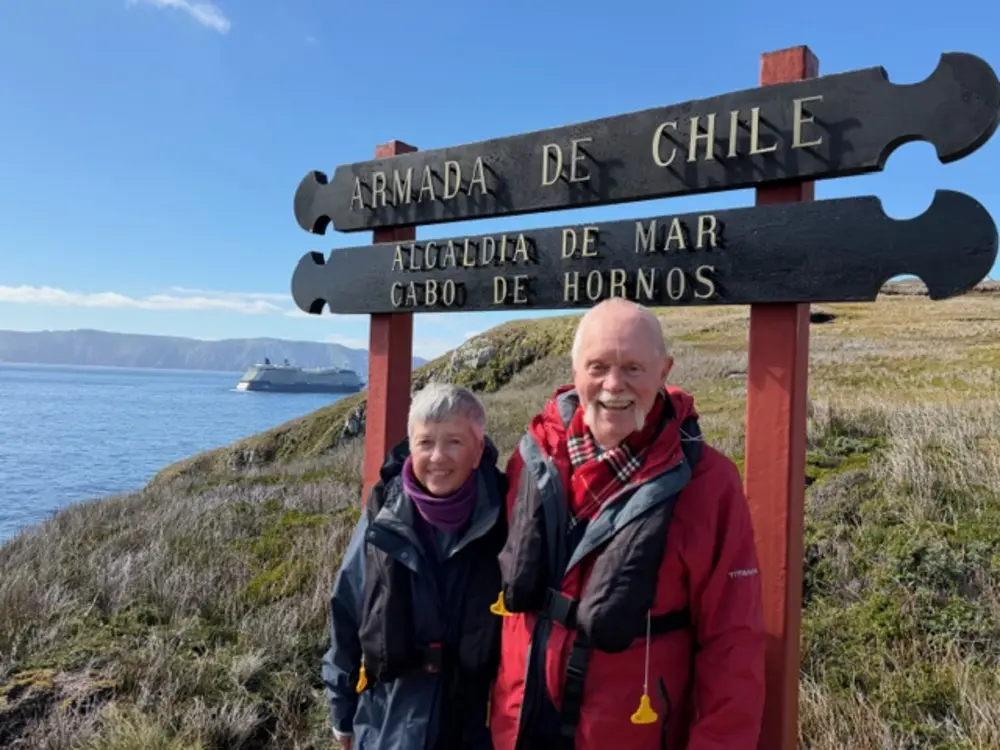 Steve Young ’74 and Sherry Gardner Young ’74 stand near a Cape Horn sign overlooking the coast of South America.