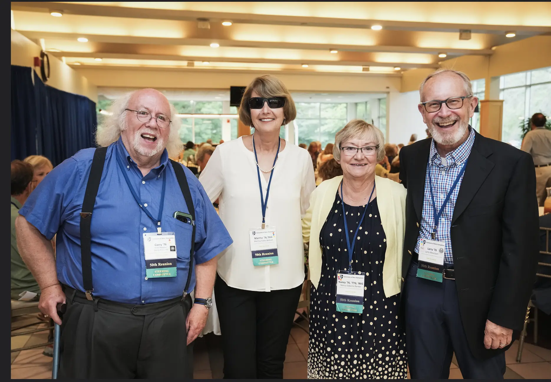 Four members of the Class of 1976 reunion committee pose together at a reception.