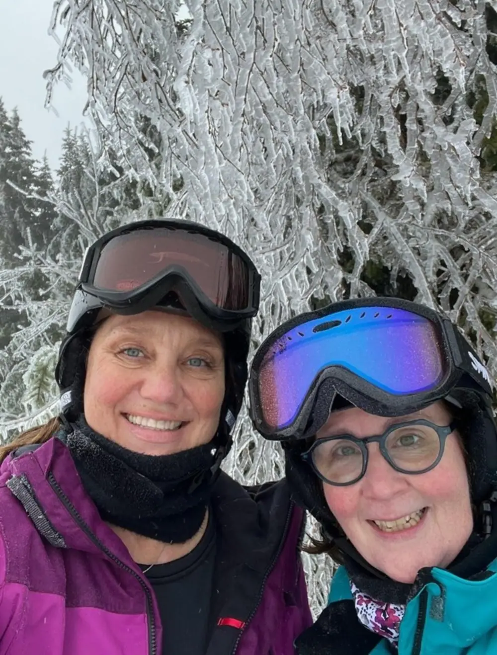 Karen O’Driscoll Beals and Katrina deRoos Hatch smile for a snowy outdoor selfie while wearing ski goggles.