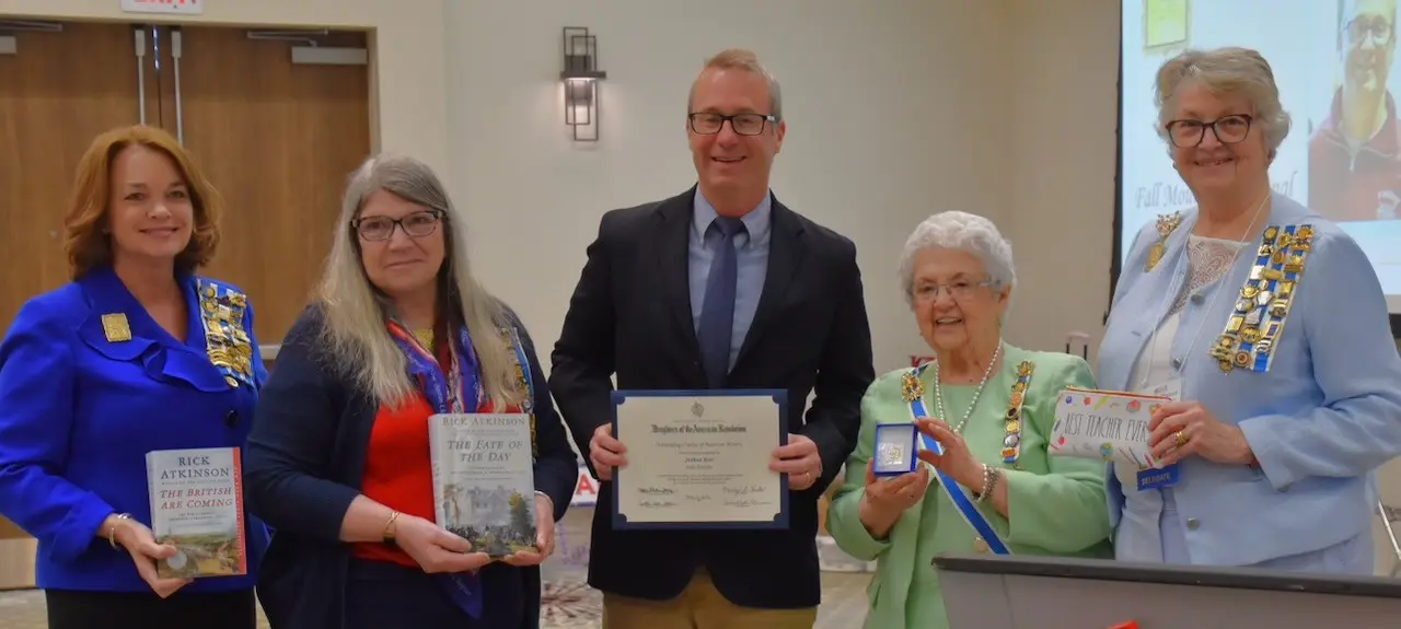 Josh Beer stands with four Daughters of the American Revolution representatives while holding his Outstanding Teacher of American History award.