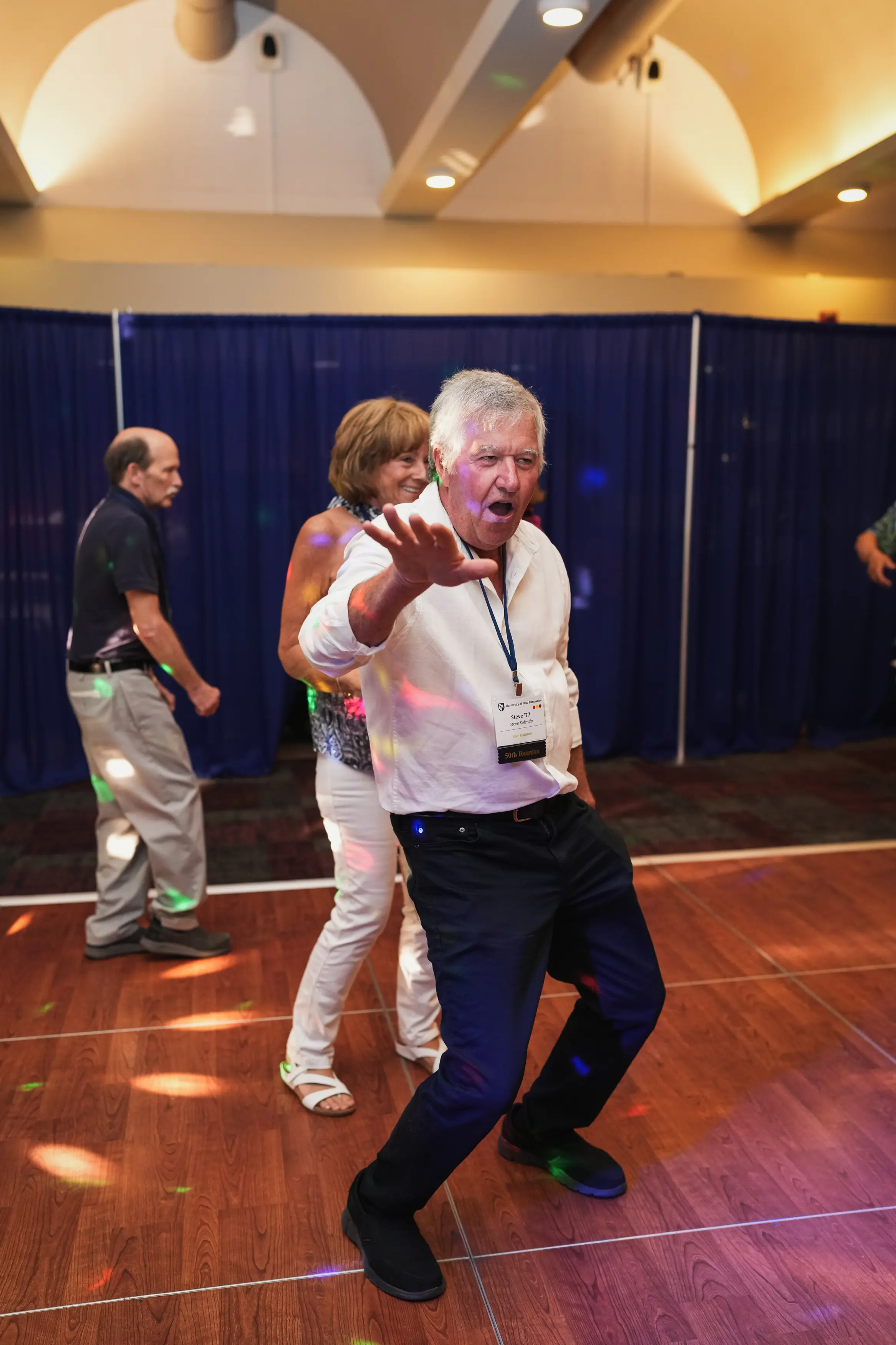 Steve Kiernan ’77 dances enthusiastically under colored lights at a reunion event.